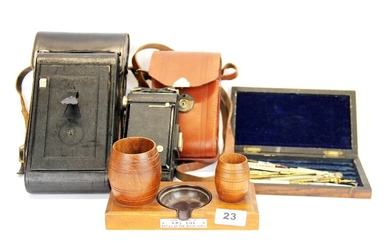A smoker's stand with bakelite ashtray made from the teak of HMS Ajax, together with two cameras and a case of drawing instruments.