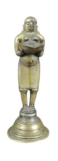 An early 20th Century African Tribal white metal figurine depicting a servant girl. The figure modelled with beaded jewellery holding a shaped serving tray. Raised on circular domed base. Measures approx; 23cm tall.