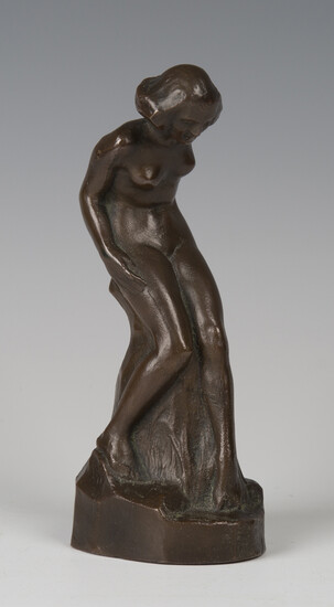 An early 20th century brown patinated cast bronze figure of a nude lady, leaning upon a rocky ledge