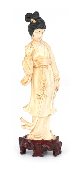 Okimono en ivoire sculpté représentant une jeune femme debout sur un socle en bois sculpté,...