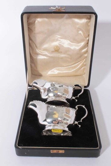 Pair of George V silver sauce boats of helmet form with faceted decoration and scroll handles, raised on oval pedestal feet, in fitted case, (Birmingham 1934)