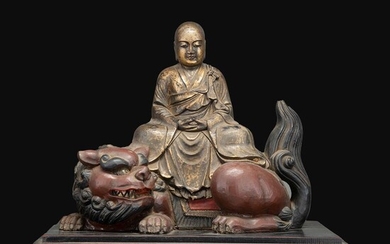 STATUE en bois laqué rouge et or, représentant un Arhat assis sur un lion. Monté sur un socle rectangulaire. (Fêle sur socle)....