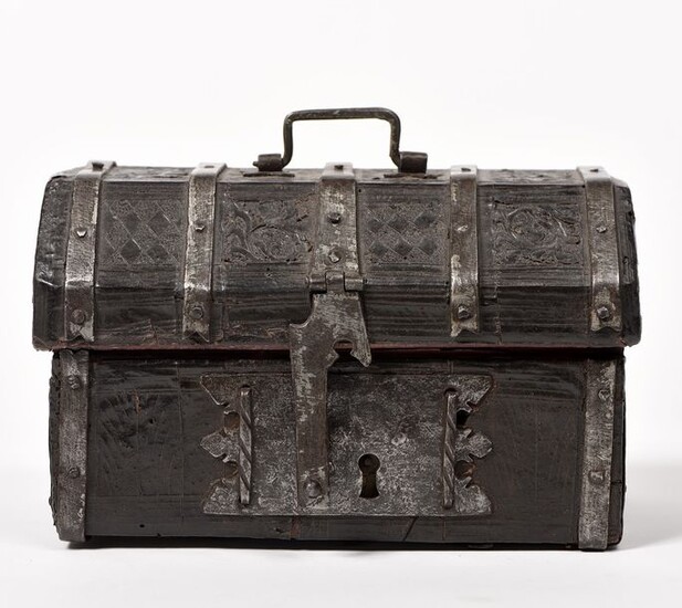 Safety box with wood core covered with leather with embossed decoration of foliage and checkerboard. Entirely reinforced with iron blades. The lid with cut-off sides surmounted by a wrought iron grip. Hasp lock and interior lined with red leather...