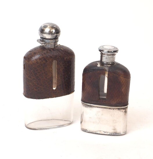 Two Victorian silver and leather mounted glass hip flasks, the larger example London, 1889, the smaller example London, 1873, both with maker's marks rubbed, the larger flask with bayonet cap and drinking cup deficient, the smaller with screw cap...