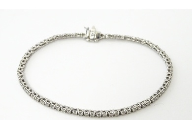 A 14ct white gold tennis bracelet set with diamonds. Approx ...