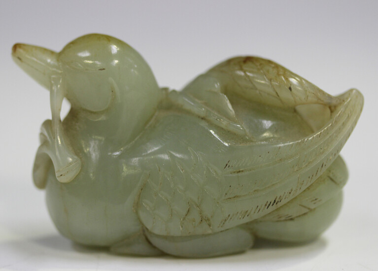 A Chinese celadon jade carving of a duck, Qing dynasty, modelled grasping a branch in its beak, the