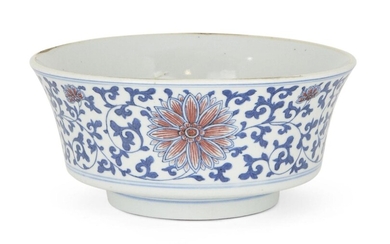 A Chinese porcelain blue and copper-red bowl, 19th century, decorated to the exterior with flowering lotus scrolls, apocryphal underglaze blue Wanli mark to base, 17cm diameter
