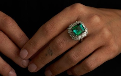 A GREEN TOURMALINE AND DIAMOND BALLERINA RING in platinum, set with an octagonal step cut green t...