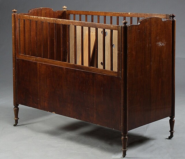A late 19th century crib of veneered and solid walnut with later bottom. H. 106 cm. L. 126 cm. W. 65 cm.