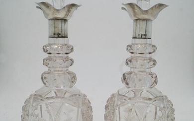 A pair of cut glass decanters and stoppers with silver collars, Sheffield, 1924, probably Walker & Hall, marks rubbed, the necks with faceted graduating rings above faceted and star cut bodies, 29cm high (2)