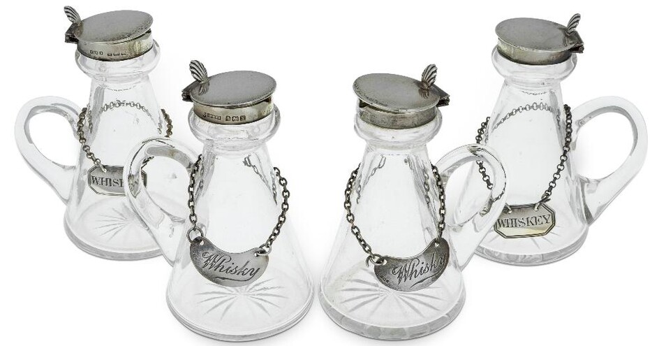 A set of four silver mounted whisky noggins, Birmingham, 1923, Cornelius Desormeaux Saunders & James Francis Hollings Shepherd, of conventional conical glass form with star cut bases, the silver collars to hinged lids with shell thumbpieces, 10cm...