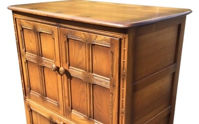 An Ercol elm Old Colonial pattern cabinet, the rounded rectangular...