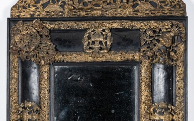 Miroir biseauté dans un encadrement à fronton en bois noirci orné de laiton à motifs...