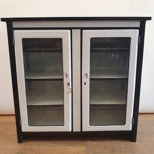 A 1920s white and black enamel cabinet, having two glazed do...