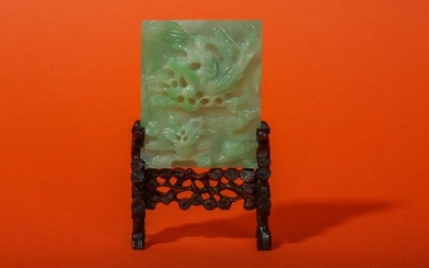 A CHINESE APPLE-GREEN JADEITE MINIATURE TABLE SCREEN. Early 20th Century Deeply carved to one side with an Immortal maiden seated on a phoenix among clouds, the reverse incised with a sage on a terrace, raised on a fitted stand carved and pierced as...