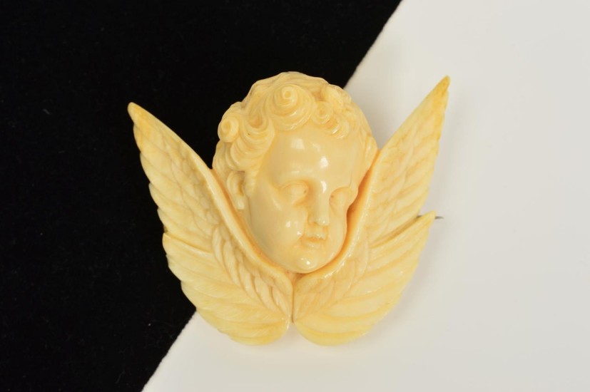 A MID VICTORIAN CARVED IVORY CHERUB BROOCH, carved in relief...