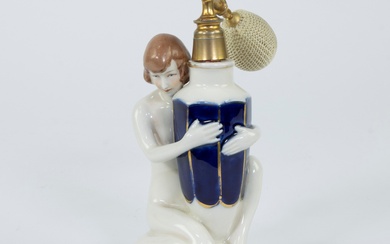 A Royal Dux art deco fine porcelain perfume bottle depicting a nude woman holding a faceted vase decorated with blue and gold enamel, marked at the bottom with a raised pink triangle.