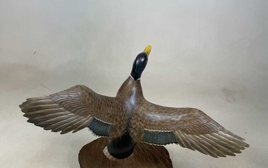 A carved wooden duck on simple sliced log section 57cm...