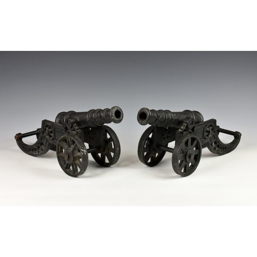 A pair of heavy cast metal fireside cannons, black painted o...