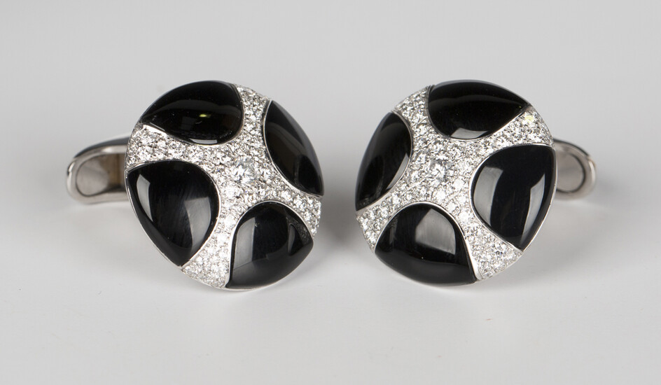 A pair of white gold, black onyx and diamond dress cufflinks, each circular front with a curved cruc