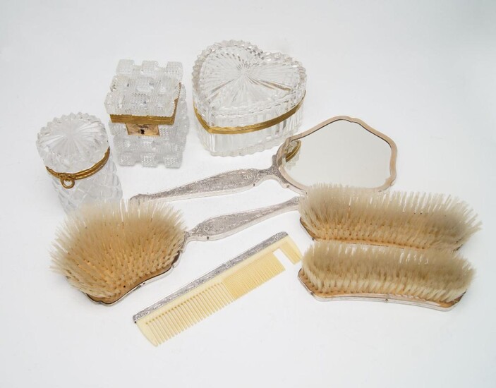 A ruby and red gem-set dressing table set, stamped 800 for silver, comprising a hand mirror and four brushes, each chased with a gem-set bouquet of flowers to reverse, together a comb of similar design (unmarked, damaged) and three gilt metal...