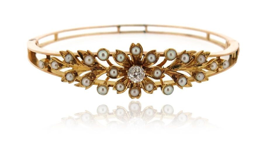 An Edwardian seed pearl and diamond bangle, of laurel design in yellow gold, 5.7cm inner diameter