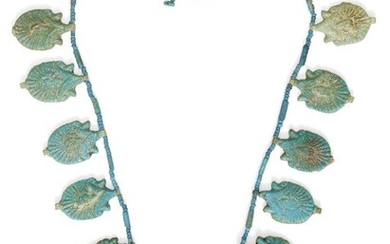 An Egyptian blue glazed faience lotus flower necklace Amarna Period, mid-14th Century B.C. Composed of twelve lotus flower amulets, each amulet of blue-green faience, with moulded decoration on one side and suspension loop at the top and the...