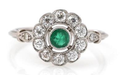 An emerald and diamond ring set with a circular-cut emerald weighing app....