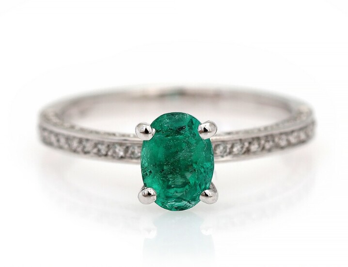 NOT SOLD. An emerald and diamond ring set with an emerald encircled by numerous diamonds,...
