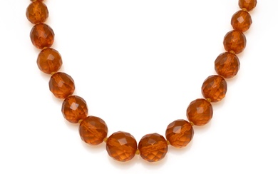 Collier composé d'une chute de perles facettées en résine imitant l'ambre. Il est agrémenté d'un...