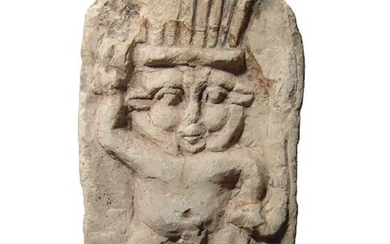 An Egyptian limestone relief depicting standing Bes