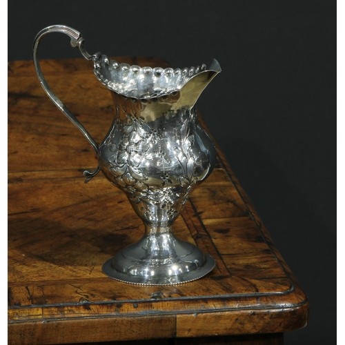 A George III silver helmet shaped jug, embossed overall with...