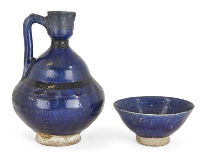 A Kashan cobalt blue glazed pottery ewer, Iran, 12th century, on spreading foot, the body rising in tow sections, restored to spout, 24cm. high and a cobalt glazed conical pottery bowl, 14.3cm. diam. (2) Provenance: Private family collection...
