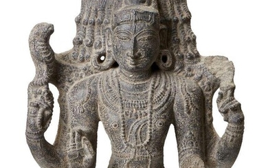 A black stone sculpture of Shiva, India, 19th century in a 10th century style, carved wearing a bejewelled tiered tiara, the elegant rounded face with almond eyes, straight nose and bow lips, and flanked with pendulous earlobes, wearing strands of...