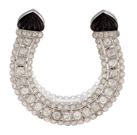 A diamond and onyx horseshoe clip brooch, set with a triple row of old-brilliant-cut diamonds, in pierced mount to domed melon-cut black onyx terminals, clip fitting, approx. width 3.9cm (VAT charged on hammer price)