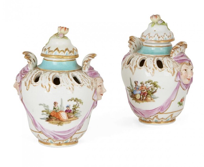 A pair of Berlin porcelain two-handled pot pourri vases and covers, late 19th century, each painted with a vignette of figures in a landscape, the mask head handles with puce drapery, blue sceptre mark, 14cm high (2)