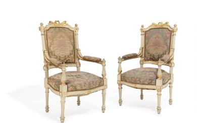 A pair of circa 1900 white painted and gilded Louis XVI style armchairs, richly carved with bows and foliage. (2)