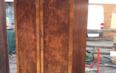 A twin-domed walnut wardrobe with moulded cornice above panelled doors...