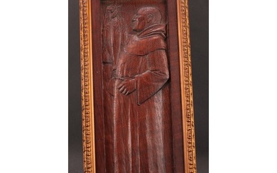 An Arts and Crafts oak panel, carved in relief with a monk i...