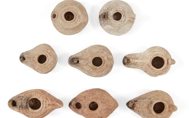 Eight Syrian-Palestinian pottery oil lamps Circa 5th-7th Century A.D Six with extended nozzles, sloping shoulders and worn moulded relief, one with a cross on the underside of the base, another with line and dot motifs, and two of circular form...
