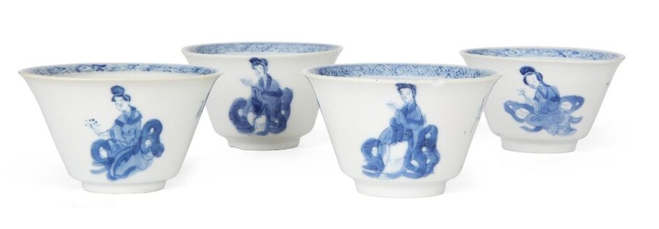 Four Chinese blue and white 'ladies and boys' tea cups, Kangxi period, each of tapered form standing on a short foot rising to a flared rim, painted to the internal with a landscape scene to the central roundel below a key fret band to the rim...