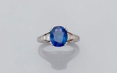 Ring in white gold, 750 MM, set with a beautiful cushion-cut sapphire weighing 6.15 carats, Ceylon origin, between two palmettes highlighted with falling baguette-cut diamonds, GGT certificate, size: 54, weight: 6.15gr. rough.