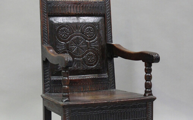 A 17th century oak Wainscot armchair, the carved panel back above a solid seat, on bobbin turned leg