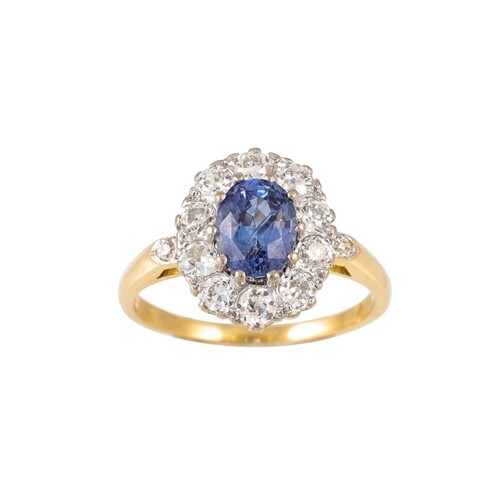 A SAPPHIRE AND DIAMOND CLUSTER RING, the oval sapphire to an...