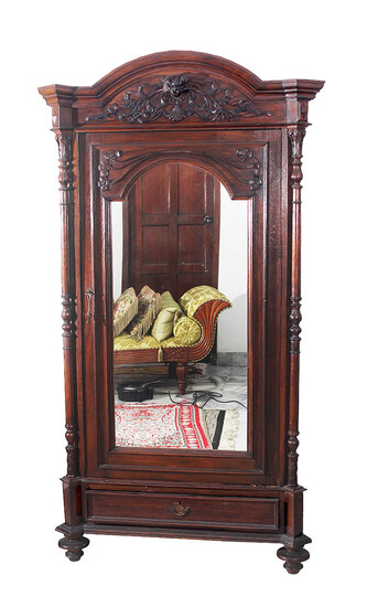 A late 19th - early 20th century carved teak cupboard with mirror