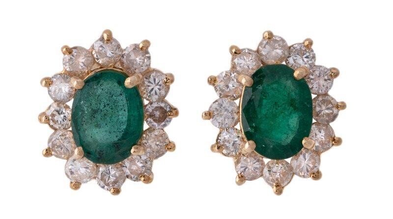 A pair of emerald and diamond earrings, cluster design, each centring on an oval emerald, framed by brilliant-cut diamonds, clip and post fittings