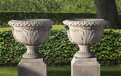 A pair of substantial carved limestone urns on plinths
