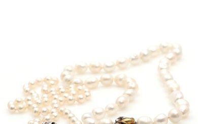 A pearl necklace set with numerous cultured pearls, mounted with 14k gold...