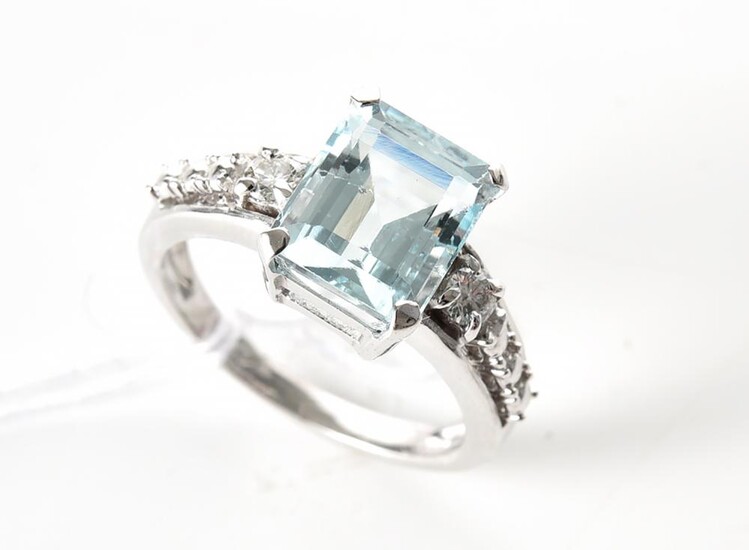 AN AQUAMARINE AND DIAMOND RING IN 18CT WHITE GOLD, THE RECTANGULAR CUT AQUAMARINE WEIGHING 3.15CTS, SHOULDERED BY TWO ROUND BRILLIANT..