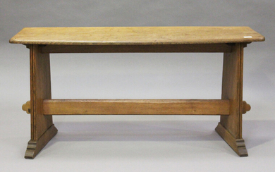 An early 20th century Arts and Crafts oak window seat, the shaped top raised on reeded plank support